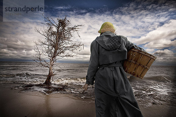 Kaukasische Frau trägt Korb am windigen Strand