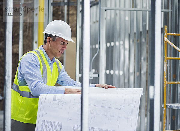 Kaukasischer Architekt liest Baupläne auf einer Baustelle