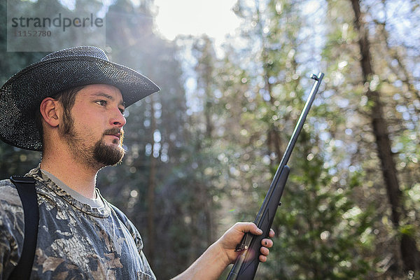 Kaukasischer Jäger mit Gewehr im Wald