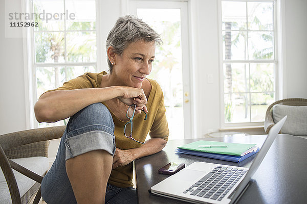 Frau benutzt Laptop im Wohnzimmer