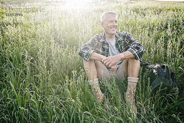 Älterer kaukasischer Mann sitzt auf einem grasbewachsenen Hügel