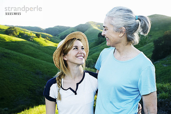 Kaukasische Mutter und Tochter lächelnd auf einer ländlichen Hügelkuppe