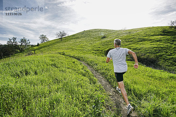 Älterer kaukasischer Mann joggt auf einem Feldweg