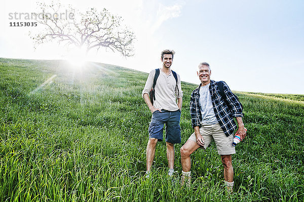 Kaukasischer Vater und Sohn stehen auf einem grasbewachsenen Hügel