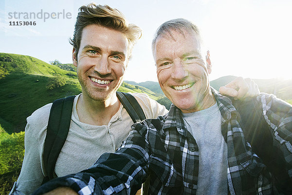 Kaukasischer Vater und Sohn machen ein Selfie auf einer ländlichen Hügelkuppe