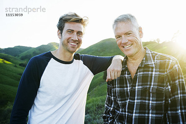 Kaukasischer Vater und Sohn lächelnd auf einer ländlichen Hügelkuppe