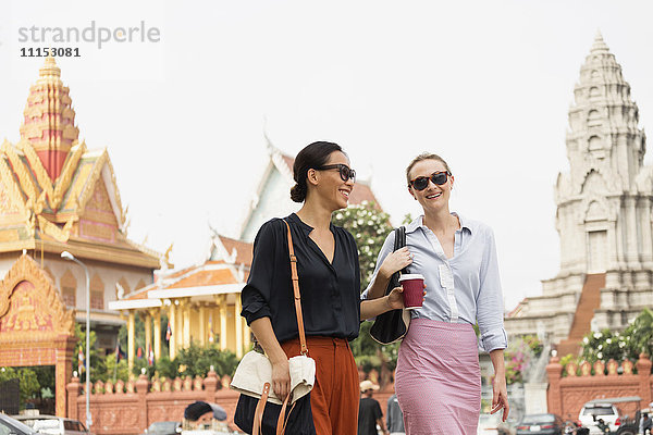 Geschäftsfrauen gehen an einem verzierten Tempel vorbei  Phnom Penh  Kambodscha