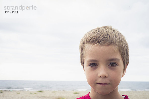 Kaukasischer Junge mit ernster Miene am Strand