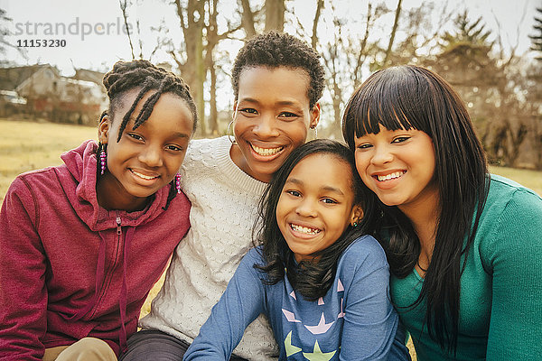 Schwarze Mutter und Töchter sitzen im Freien