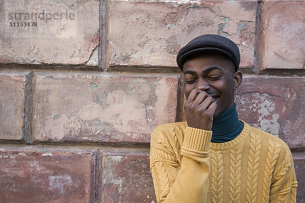 Schwarzer Mann lachend in der Nähe einer Ziegelmauer