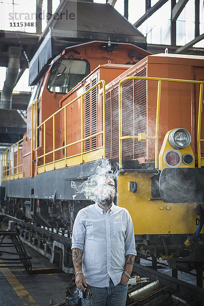 Kaukasischer Mann bläst Rauch im Rangierbahnhof