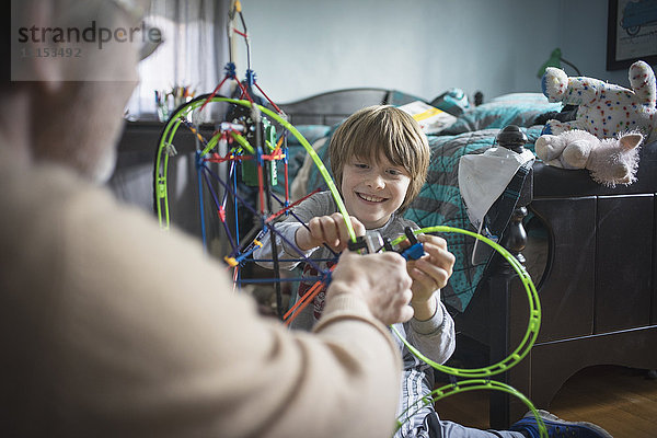 Kaukasischer Vater und Sohn spielen mit Spielzeug im Schlafzimmer