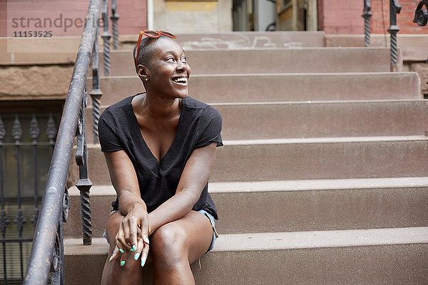 Schwarze Frau sitzt auf einer städtischen Treppe