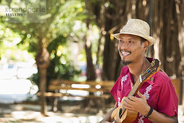 Hispanischer Musiker spielt Ukulele im Park