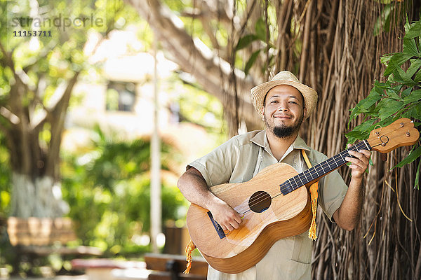 Hispanischer Musiker spielt Gitarre im Park