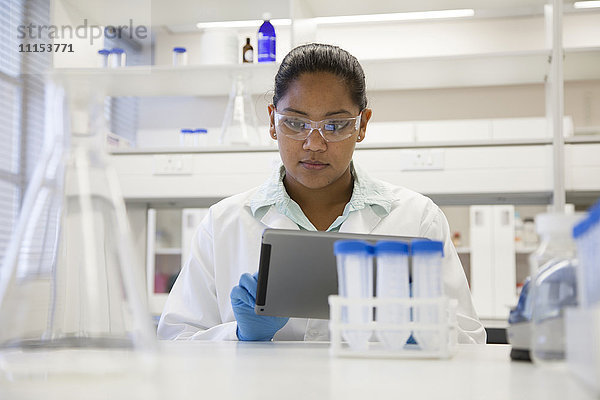 Gemischtrassige Wissenschaftlerin benutzt digitales Tablet im Labor