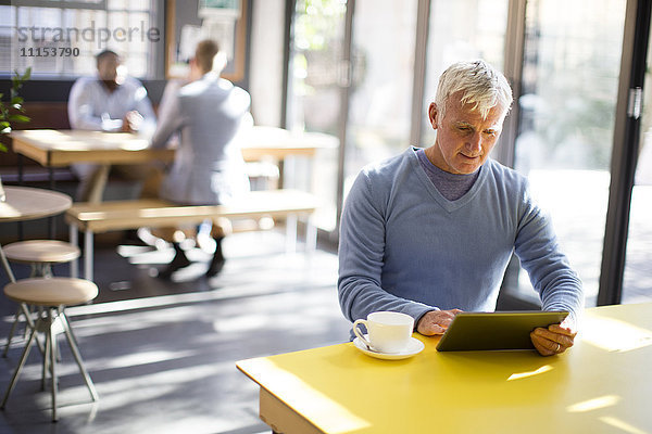 Älterer Mann benutzt digitales Tablet in einem Cafe