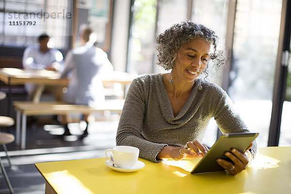Ältere Frau benutzt digitales Tablet in einem Café
