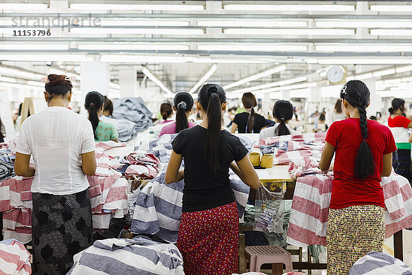 Asiatische Arbeiterinnen nähen Kleidung in einer Bekleidungsfabrik