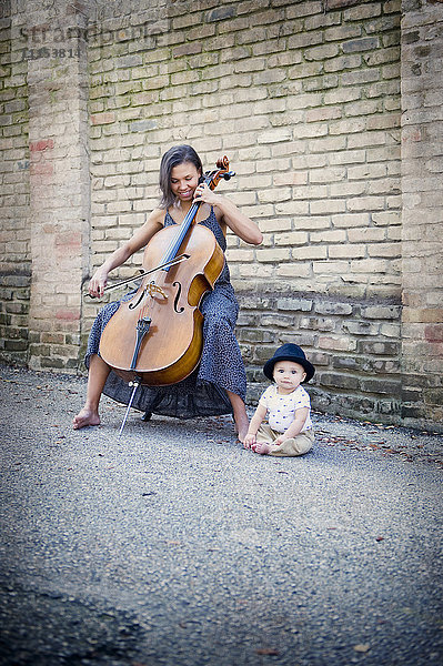 Gemischtrassiger Musiker spielt Cello mit kleiner Tochter