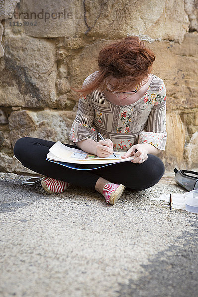 Kaukasisches Mädchen zeichnet auf Betonboden