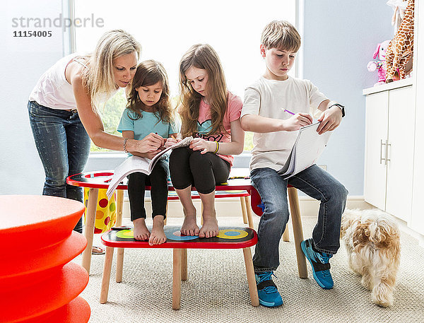 Kaukasische Familie zeichnet am Tisch im Spielzimmer