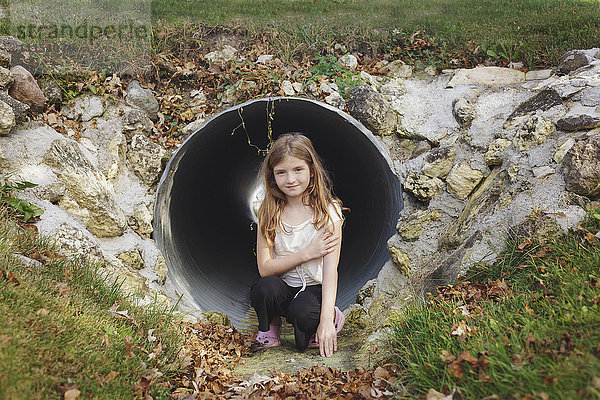 Kaukasisches Mädchen klettert im Abwasserkanal