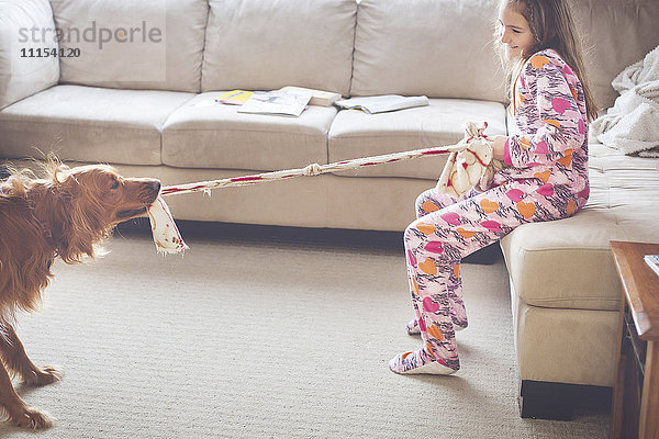 Kaukasisches Mädchen spielt mit Hund im Wohnzimmer