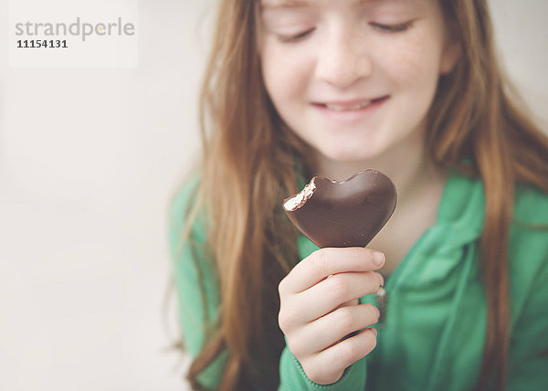 Kaukasisches Mädchen isst herzförmige Schokolade