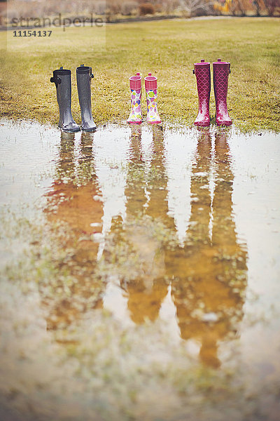 Reflexion von Menschen aus Regenstiefeln in einer Pfütze