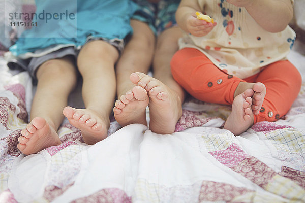 Nahaufnahme der Füße von Geschwistern auf einer Decke