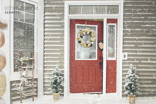 Kaukasische Frau öffnet Tür zu Schnee