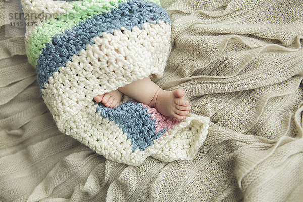 Nahaufnahme der Füße eines neugeborenen Babys  eingewickelt in eine Decke