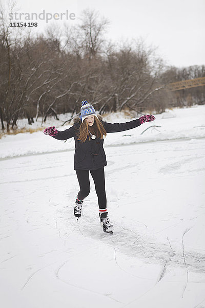 Kaukasisches Teenager-Mädchen beim Schlittschuhlaufen auf einem zugefrorenen See