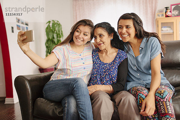 Großmutter und Enkeltöchter machen ein Selfie auf dem Sofa