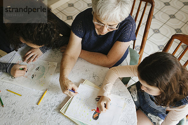 Großmutter und Enkelkinder zeichnen am Tisch