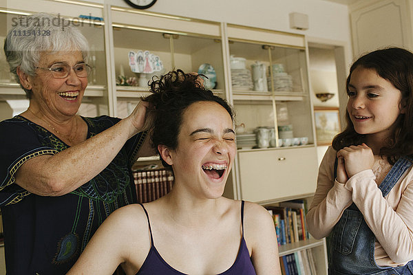 Großmutter frisiert die Haare ihrer Enkelin im Esszimmer