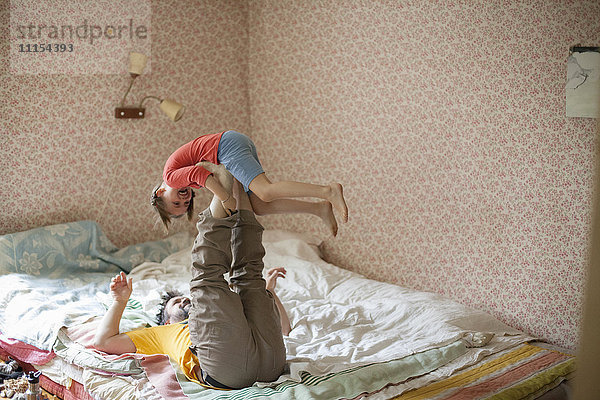 Kaukasischer Vater und Tochter spielen auf dem Bett