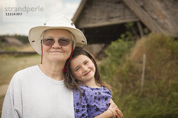 Kaukasische Großmutter umarmt ihre Enkelin im Hinterhof