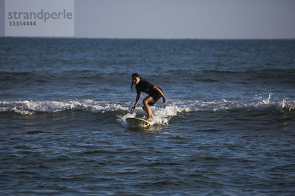 Hispanische Frau beim Surfen im Meer