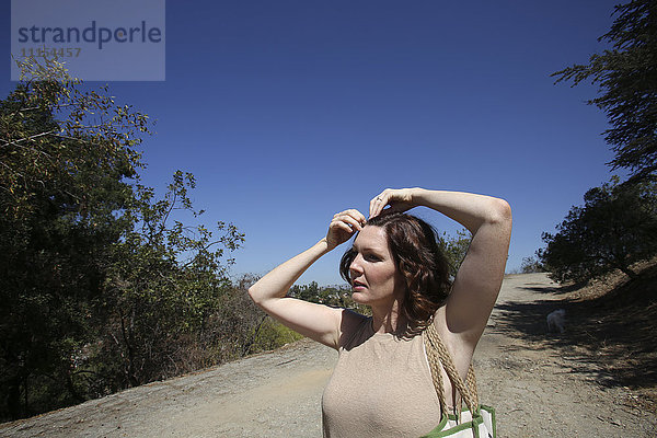 Kaukasische Frau  die ihr Haar auf einem Feldweg feststeckt