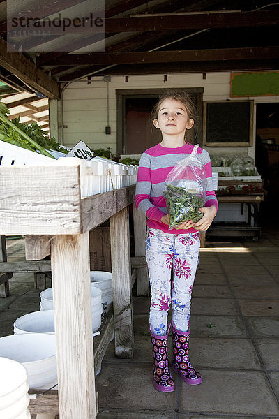 Ein gemischtrassiges Mädchen hält eine Tüte mit Produkten auf dem Bauernmarkt