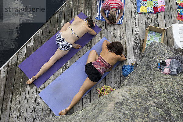 Frauen üben Yoga auf einem Holzsteg