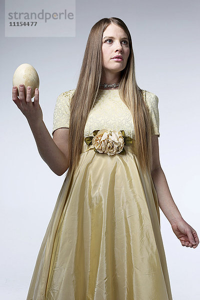 Frau im Kittel hält Ei