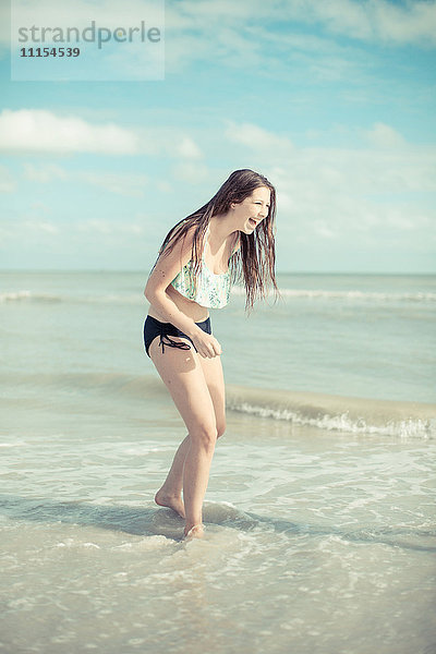 Kaukasisches Teenager-Mädchen spielt in den Wellen am Strand