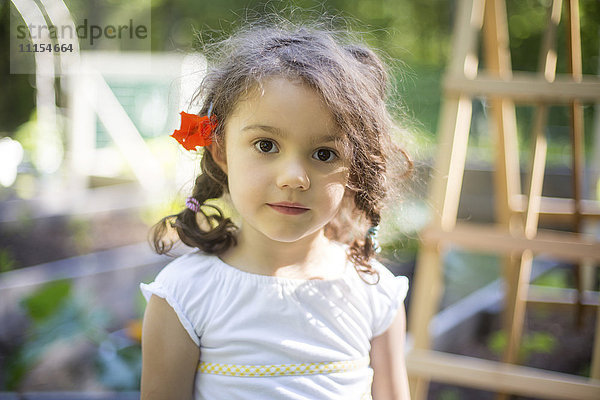 Lächelndes Mädchen mit Blume im Haar im Garten