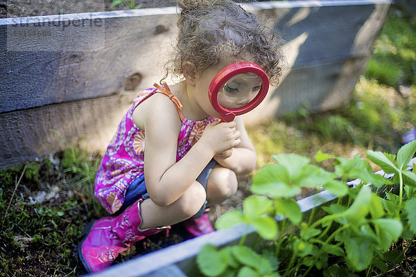 Mädchen untersucht Gartenpflanzen mit Lupe