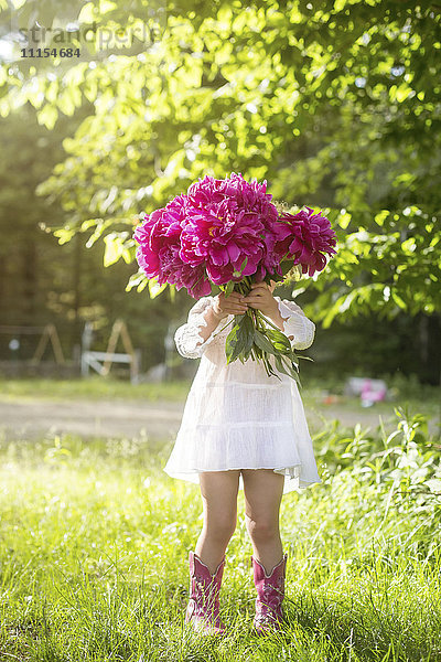 Mädchen hält Blumenstrauß im Hinterhof