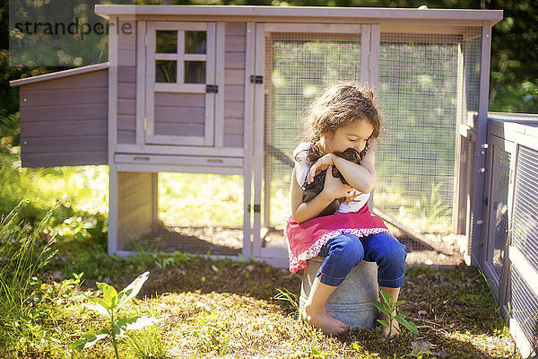 Mädchen umarmt Huhn im Bauernhof