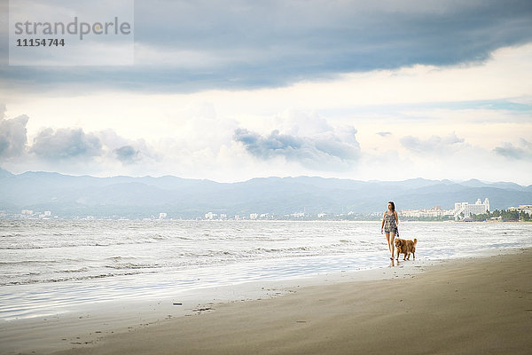 Mexiko  Nayarit  Junge Frau mit Golden Retriever Hund am Strand